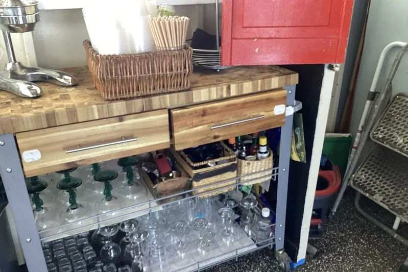 Indian River Queen Yacht Photos Pics Bar cart with glassware, utensils, and condiments, featuring a wooden countertop and storage drawers.