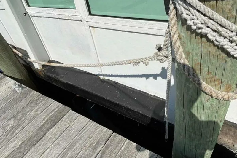 Indian River Queen Yacht Photos Pics Docked custom paddle wheel boat from 1984, secured with ropes to a wooden post.