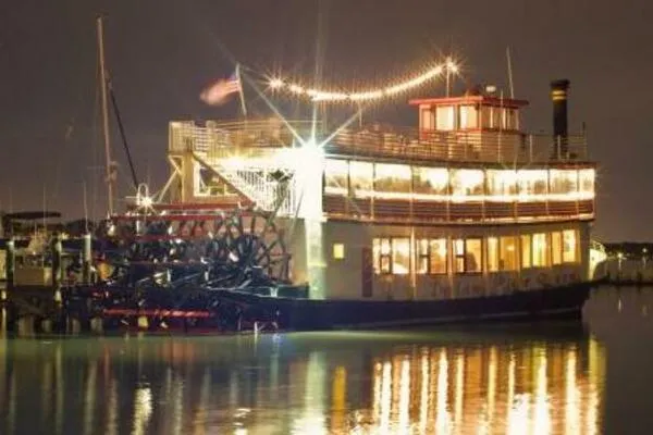 Indian River Queen Yacht Photos Pics Vintage 1984 custom paddle wheel boat illuminated at night, reflecting on calm water.