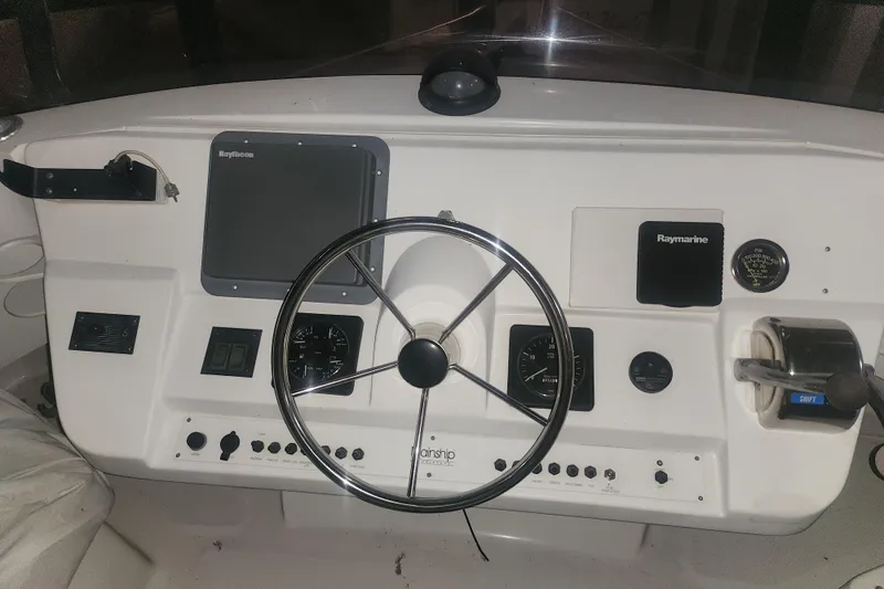 Teddy B Yacht Photos Pics 1997 Mainship 350 Trawler helm with steering wheel, Raymarine electronics, and control panel.