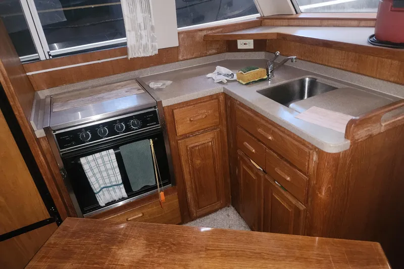 Teddy B Yacht Photos Pics 1997 Mainship 350 Trawler kitchen with stove, sink, and wooden cabinetry.