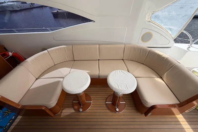  Yacht Photos Pics Luxurious seating area on 2004 Mangusta 72 yacht with beige cushions and wooden flooring.