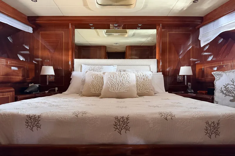  Yacht Photos Pics Luxurious bedroom interior of 2004 Mangusta 72 yacht with elegant wood paneling and plush bedding.
