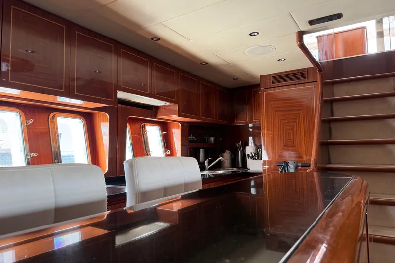  Yacht Photos Pics Luxurious interior of 2004 Mangusta 72 yacht with polished wood and modern kitchen.