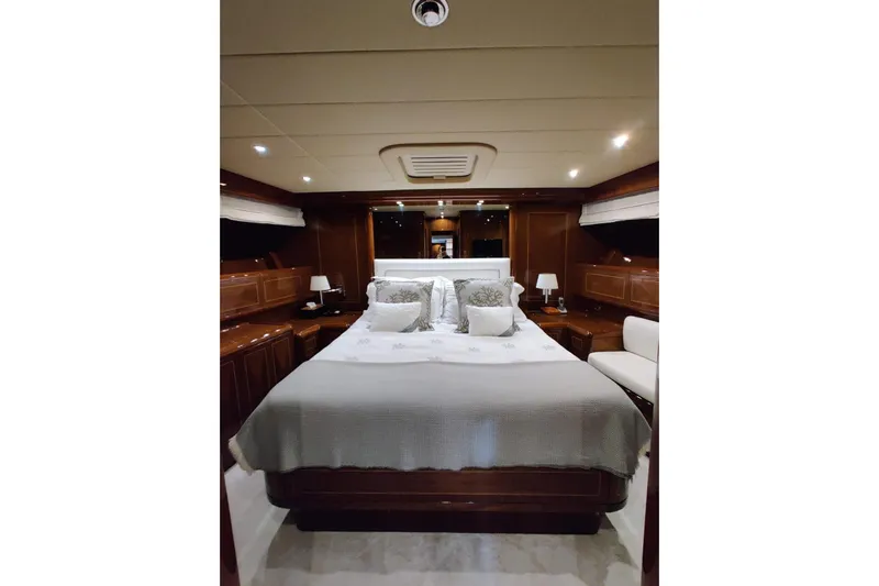  Yacht Photos Pics Luxurious bedroom interior of 2004 Mangusta 72 yacht with elegant wood finishes and cozy bedding.