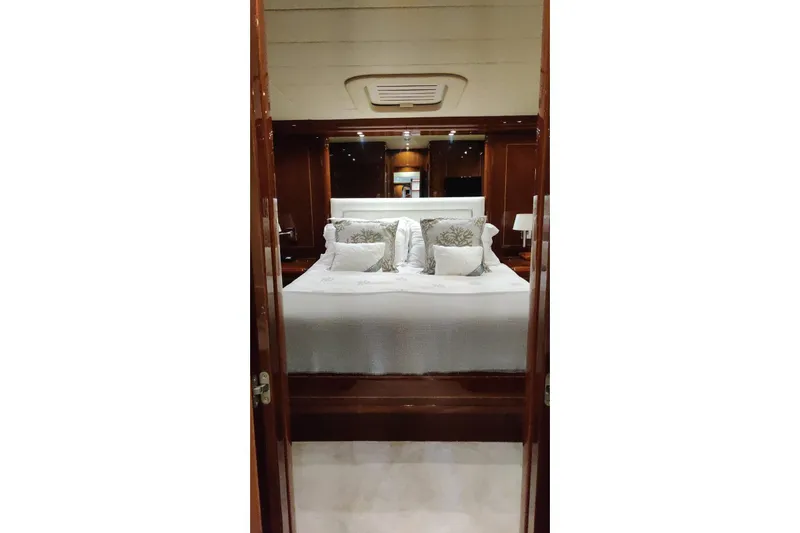  Yacht Photos Pics Luxurious bedroom interior of 2004 Mangusta 72 yacht with elegant bedding and wood finishes.
