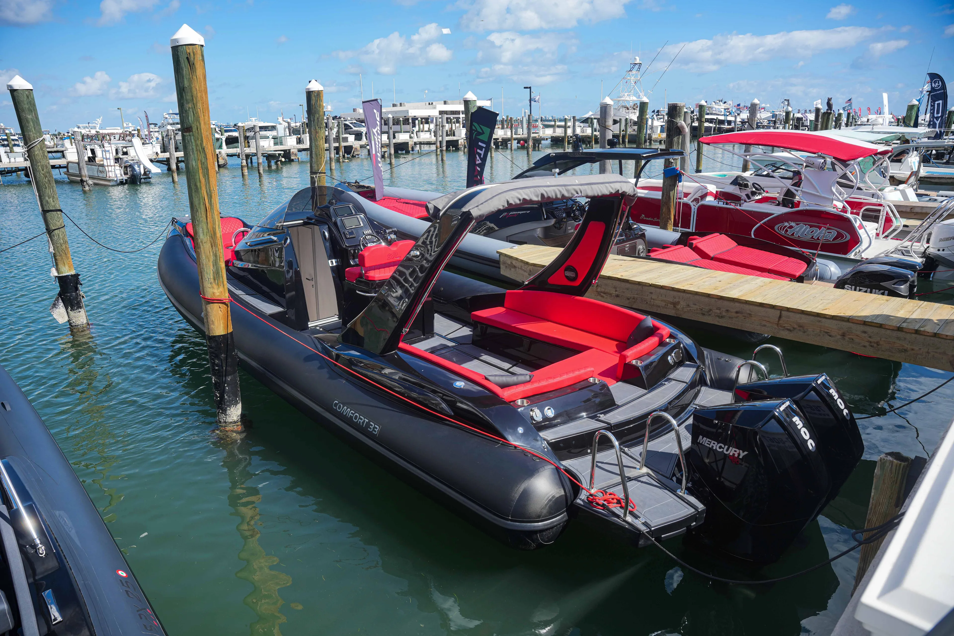 2025 Sea Prop COMFORT 33 boat docked at marina with red seating and Mercury outboard motor.
