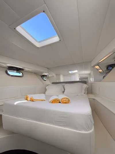 Azaxaki Yacht Photos Pics Luxurious cabin interior of 1995 Magnum 50 Bestia yacht with skylight and plush bedding.