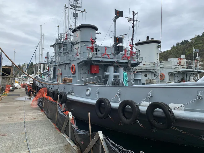  Yacht Photos Pics 1955 L-T 100 Steel Army Tugboat docked at a harbor, overcast sky.