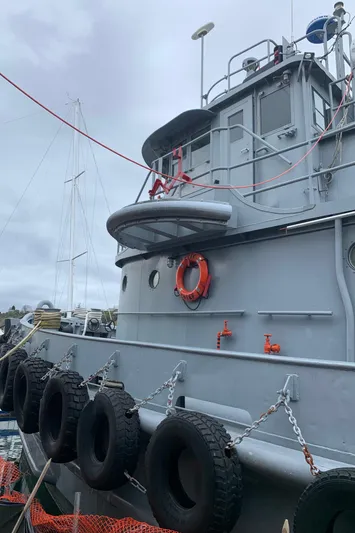  Yacht Photos Pics 1955 L-T 100 Steel Army Tugboat docked, featuring life preserver and tires for protection.