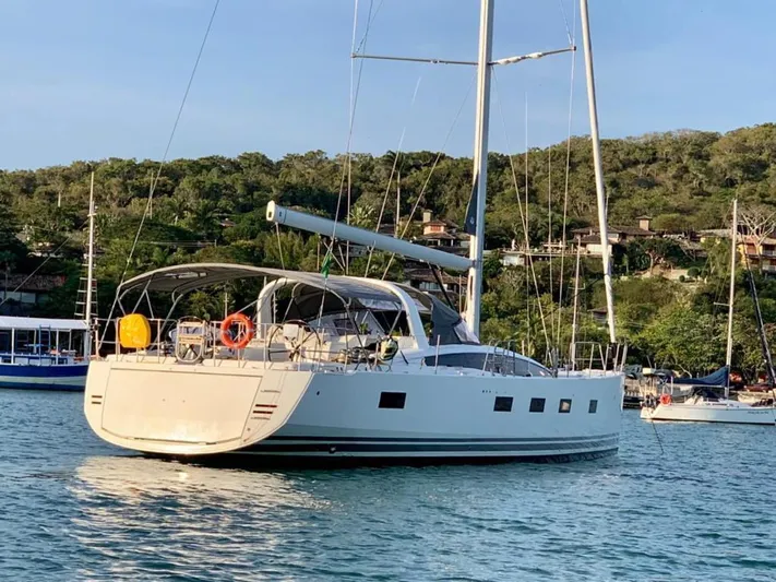  Yacht Photos Pics 2021 Jeanneau 64 yacht anchored in scenic bay with lush green hills.