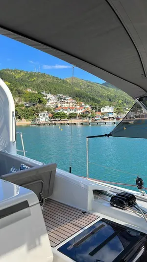  Yacht Photos Pics 2021 Jeanneau 64 yacht with scenic coastal view and clear blue water.