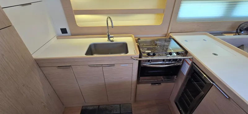 Wildflower Yacht Photos Pics Modern kitchen in 2021 Beneteau Oceanis Yacht 54 with sink, stove, and wooden cabinetry.