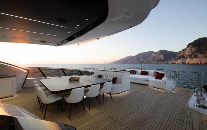  Yacht Photos Pics Luxurious 2022 Mangusta 165 REV yacht deck with elegant seating and ocean view at sunset.