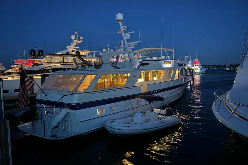 Capricho Yacht Photos Pics 1987 Burger Motoryacht docked at night, illuminated with warm lights.
