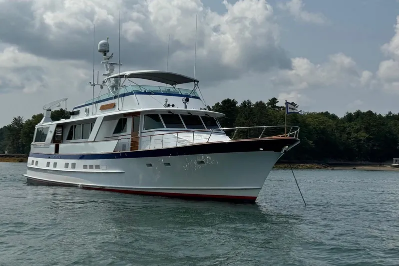 Capricho Yacht Photos Pics 1987 Burger Motoryacht anchored on calm water with forested shoreline in background.