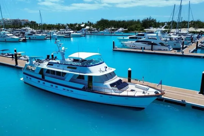 Capricho Yacht Photos Pics 1987 Burger Motoryacht docked in a vibrant marina with clear blue water.