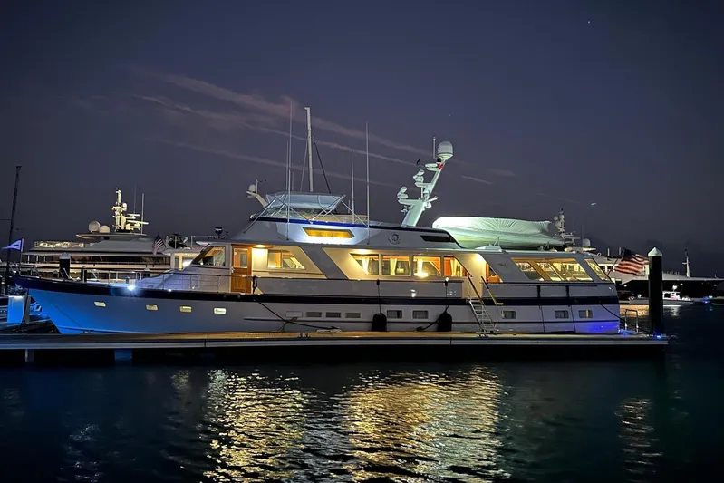 Capricho Yacht Photos Pics 1987 Burger Motoryacht illuminated at night, docked in a serene marina setting.