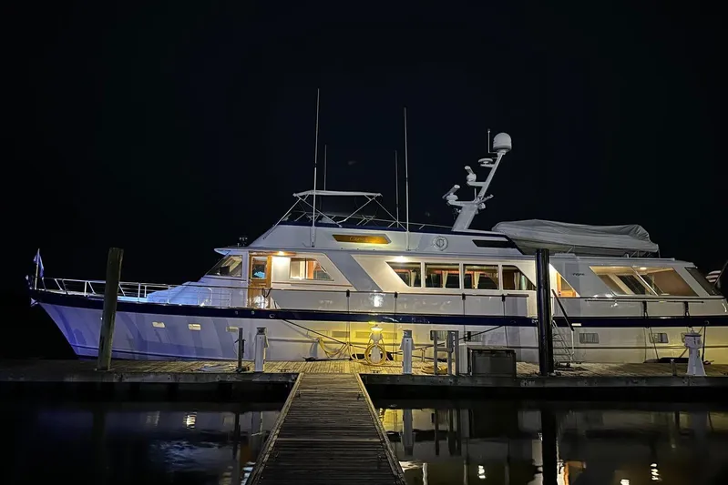 Capricho Yacht Photos Pics 1987 Burger Motoryacht docked at night, illuminated with warm lights.