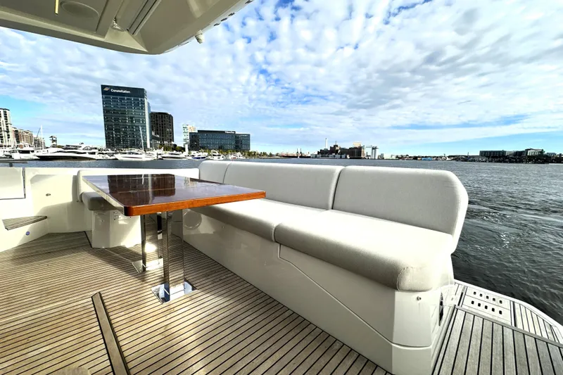 Highland Patriot Yacht Photos Pics 2023 Prestige 590 yacht deck with seating, table, and waterfront cityscape view.