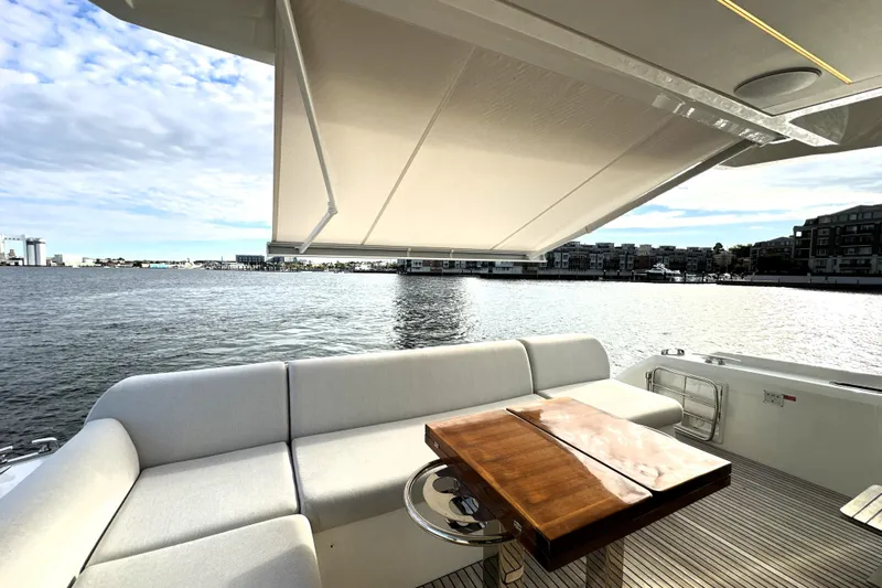 Highland Patriot Yacht Photos Pics Luxurious 2023 Prestige 590 yacht deck with seating, table, and waterfront view.
