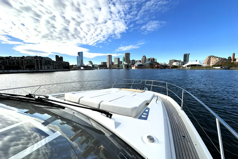Highland Patriot Yacht Photos Pics Prestige 590 yacht cruising near city skyline under blue sky, 2023 model.