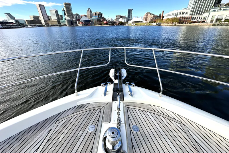 Highland Patriot Yacht Photos Pics Bow view of 2023 Prestige 590 yacht approaching city skyline over calm water.