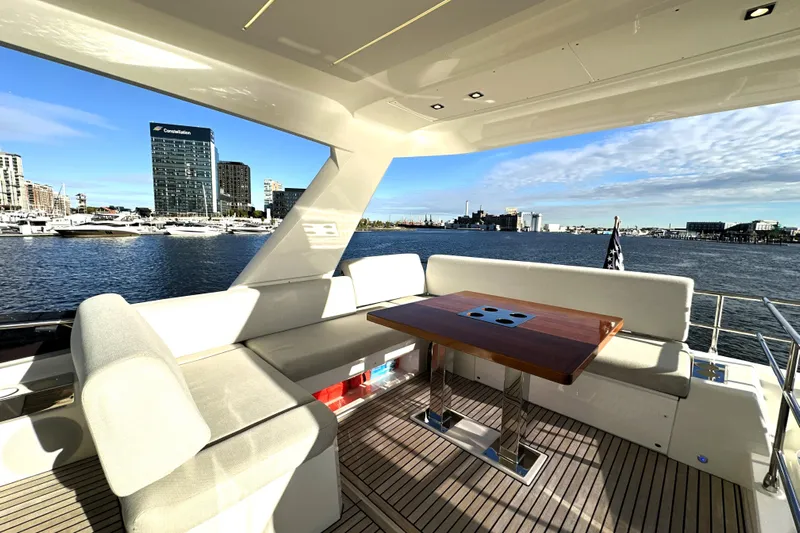 Highland Patriot Yacht Photos Pics Luxurious 2023 Prestige 590 yacht deck with seating, table, and waterfront city view.