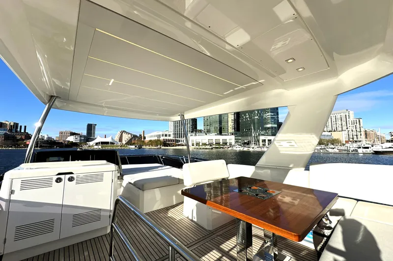 Highland Patriot Yacht Photos Pics Luxurious 2023 Prestige 590 yacht interior with city skyline view, featuring elegant seating and table.