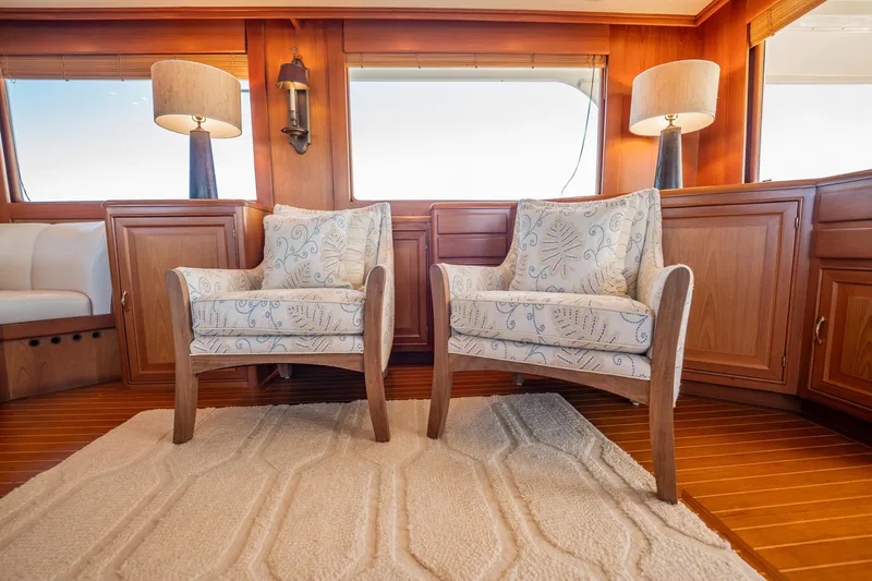 Beba Yacht Photos Pics Elegant yacht interior with two patterned armchairs, wooden cabinetry, and soft lighting. Fleming 75, 2003.