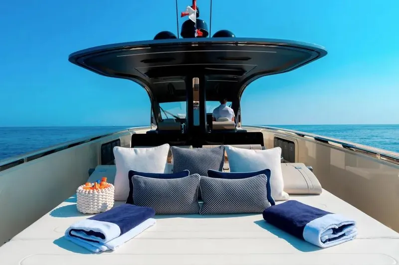 Montenegrina Yacht Photos Pics Luxurious 2023 Invictus TT460 yacht deck with cushions and towels, set against a clear blue sea.