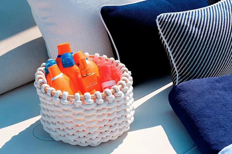 Montenegrina Yacht Photos Pics Basket of sunscreen bottles on Invictus TT460 yacht, 2023, with blue and white cushions.