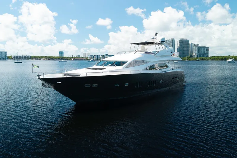 Sukha Yacht Photos Pics 2008 Sunseeker 90 Yacht cruising on a sunny day with city skyline backdrop.