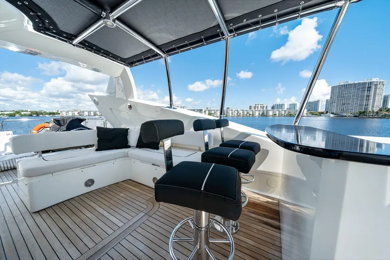 Sukha Yacht Photos Pics Luxurious 2008 Sunseeker 90 Yacht deck with seating, bar stools, and waterfront view.
