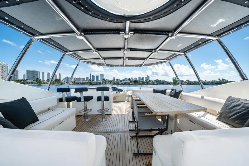 Sukha Yacht Photos Pics Luxurious 2008 Sunseeker 90 Yacht deck with seating, table, and city skyline view.