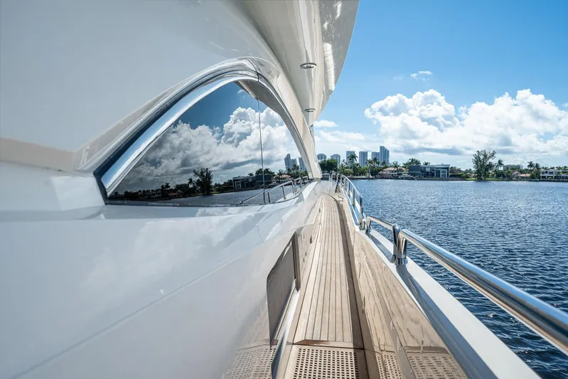 Sukha Yacht Photos Pics 2008 Sunseeker 90 Yacht on serene water, reflecting blue sky and clouds.