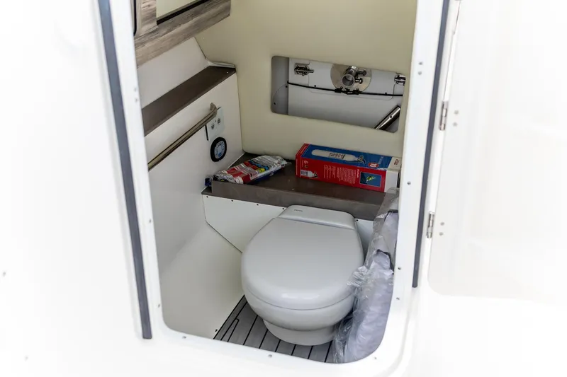  Yacht Photos Pics 2023 Edgewater 248 CX boat interior with compact toilet and storage space.