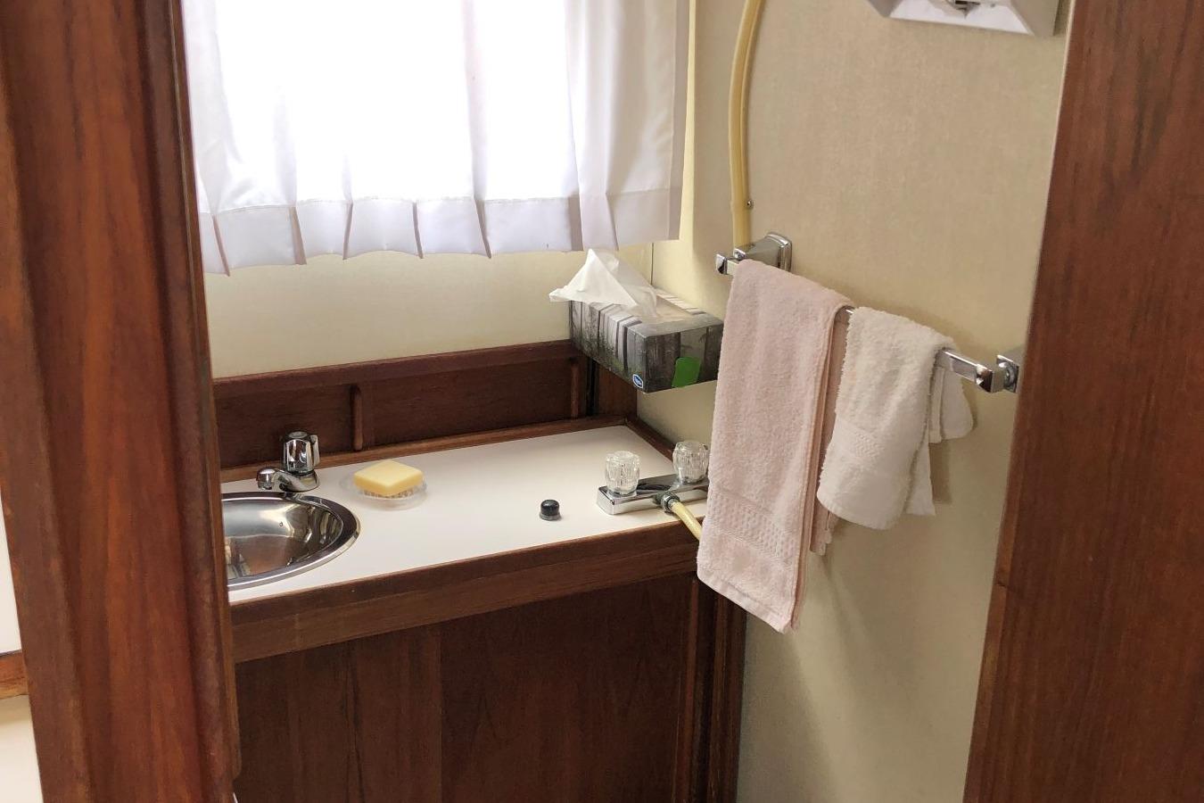 Bathroom interior of 1988 Commander 30 Command Bridge with sink, towels, and window.