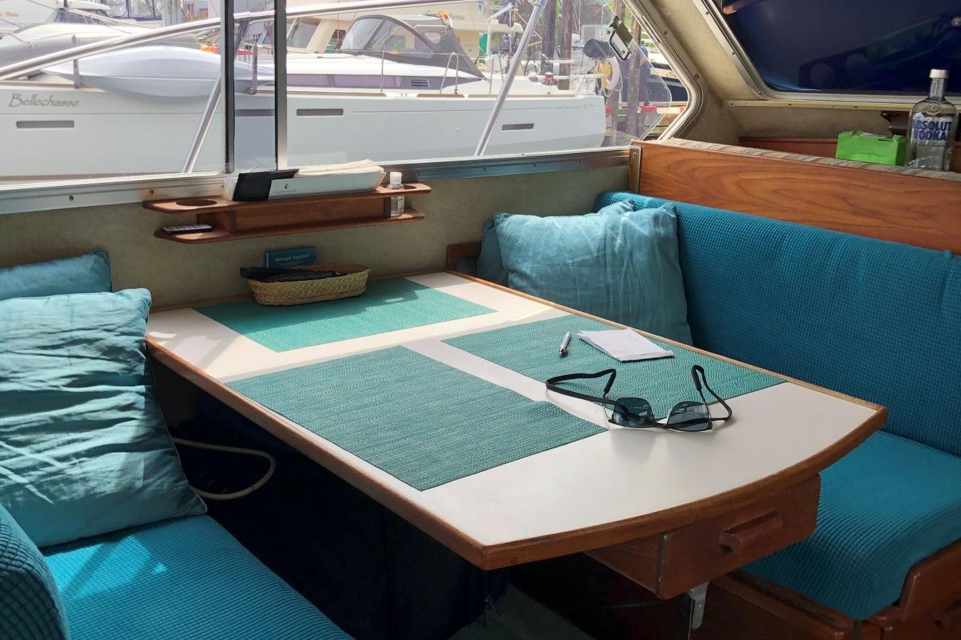 Cozy interior of 1988 Commander 30 Command Bridge with teal cushions and table setting.