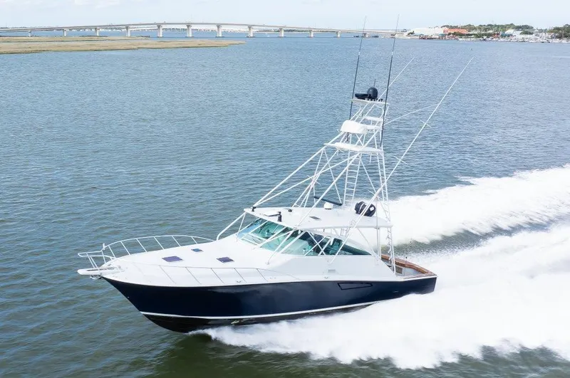 Reel Blessed Yacht Photos Pics 2006 Cabo 52 Open yacht cruising on water near a bridge.
