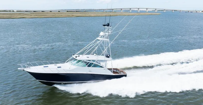 Reel Blessed Yacht Photos Pics 2006 Cabo 52 Open yacht cruising on open water near a bridge.