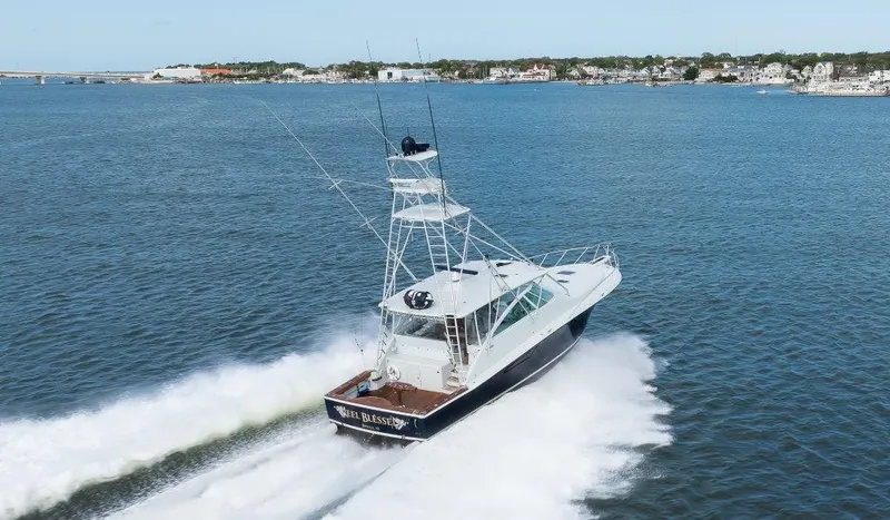 Reel Blessed Yacht Photos Pics 2006 Cabo 52 Open yacht cruising on a scenic waterway near a coastal town.