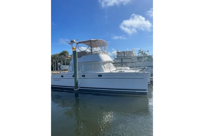On The Fly Yacht Photos Pics 2005 PDQ 34 Power Catamaran docked under clear blue sky.