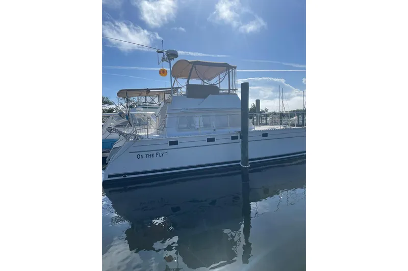 On The Fly Yacht Photos Pics 2005 PDQ 34 Power Catamaran docked under a clear blue sky.