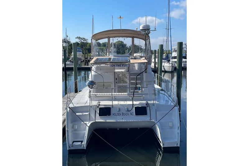 On The Fly Yacht Photos Pics 2005 PDQ 34 Power Catamaran docked at marina, rear view with clear sky.