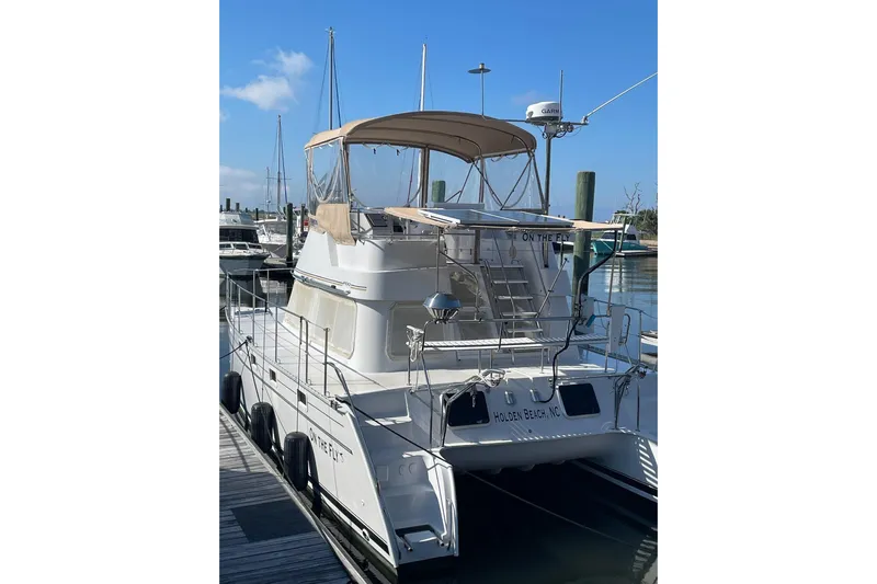 On The Fly Yacht Photos Pics 2005 PDQ 34 Power Catamaran docked at marina under clear blue sky.