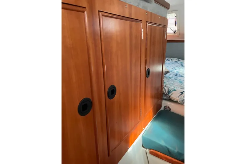 On The Fly Yacht Photos Pics Interior of 2005 PDQ 34 Power Catamaran with wooden cabinets and cozy bedding.