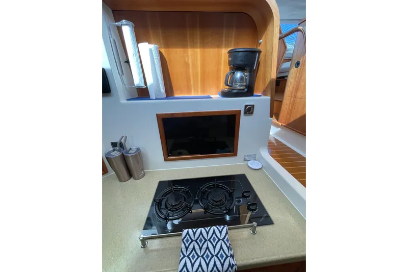 On The Fly Yacht Photos Pics Galley of 2005 PDQ 34 Power Catamaran with stove, coffee maker, and wooden cabinetry.