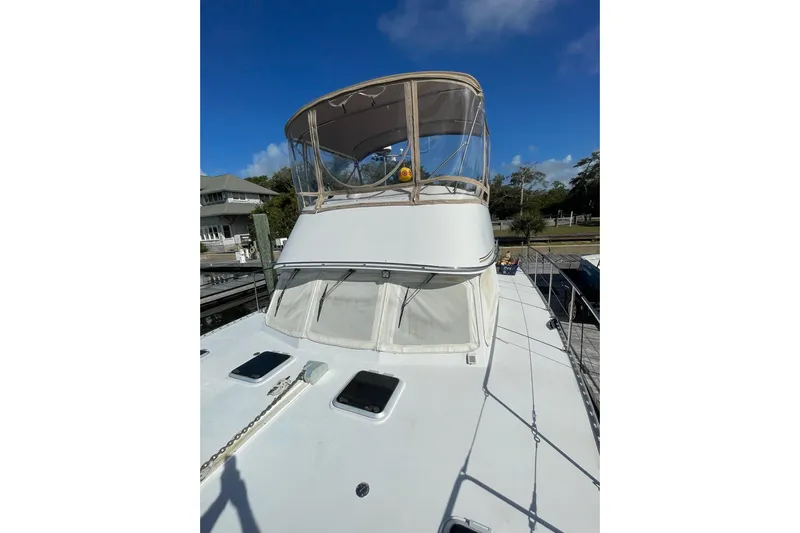 On The Fly Yacht Photos Pics 2005 PDQ 34 Power Catamaran with flybridge, docked under clear blue sky.