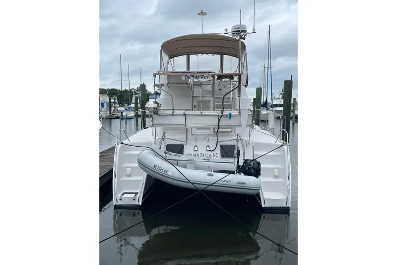 On The Fly Yacht Photos Pics 2005 PDQ 34 Power Catamaran docked at marina with inflatable dinghy.